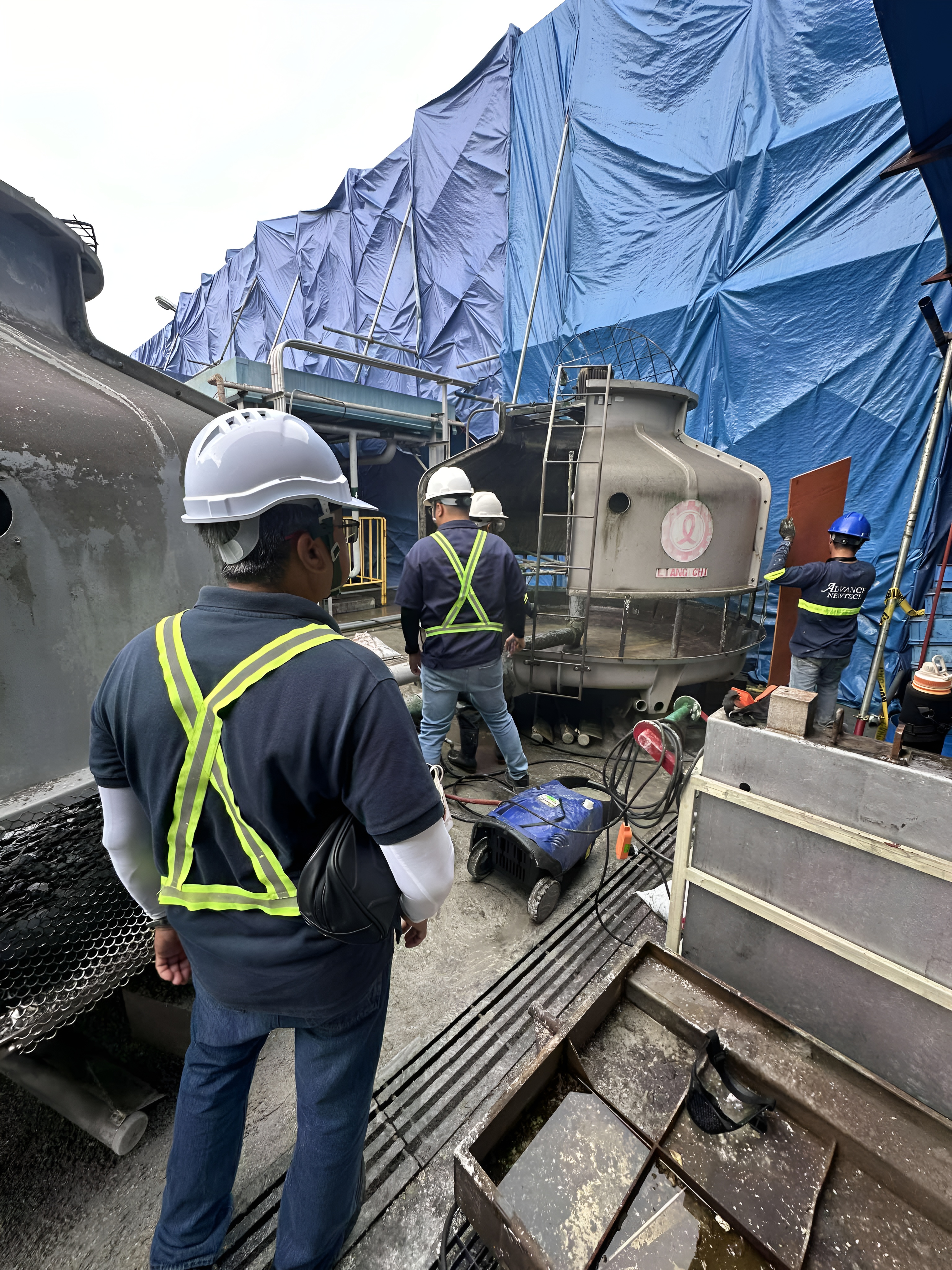 Technicians performing chemical water treatment on cooling tower system