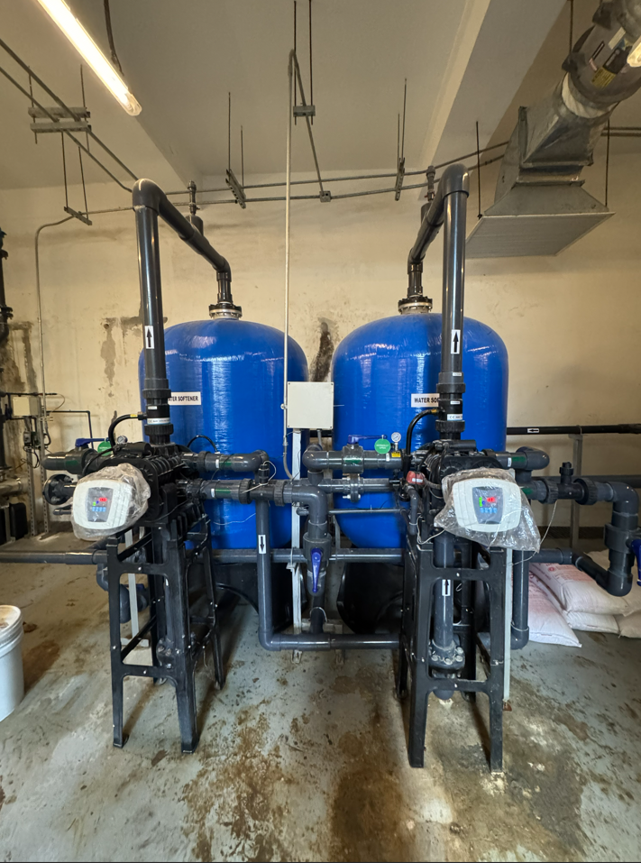 Technician performing chemical water treatment on industrial piping